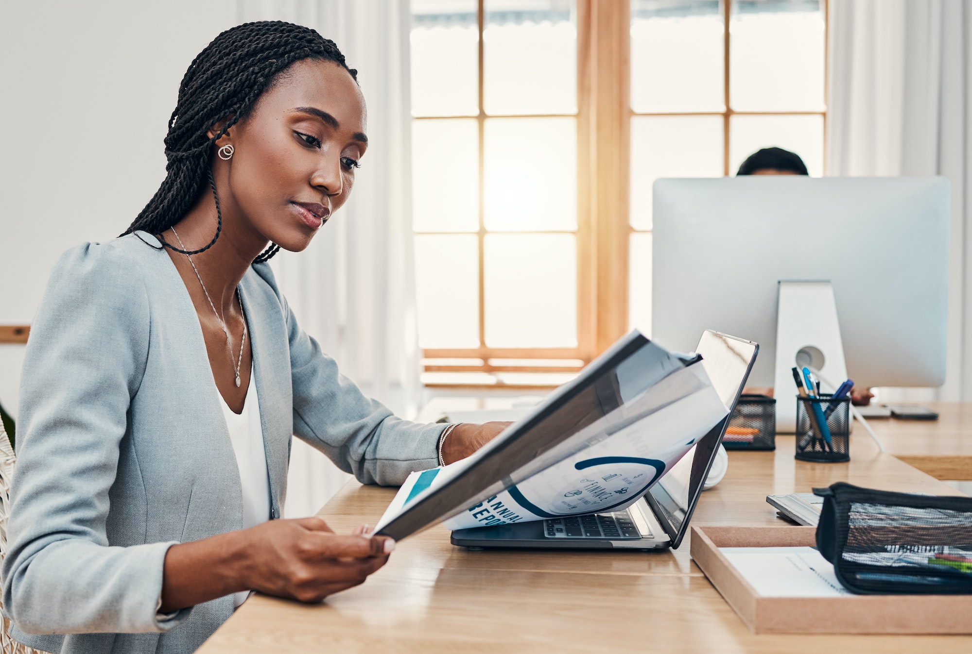 Black woman, office and book at desk reading with laptop for research, education or learning at wor